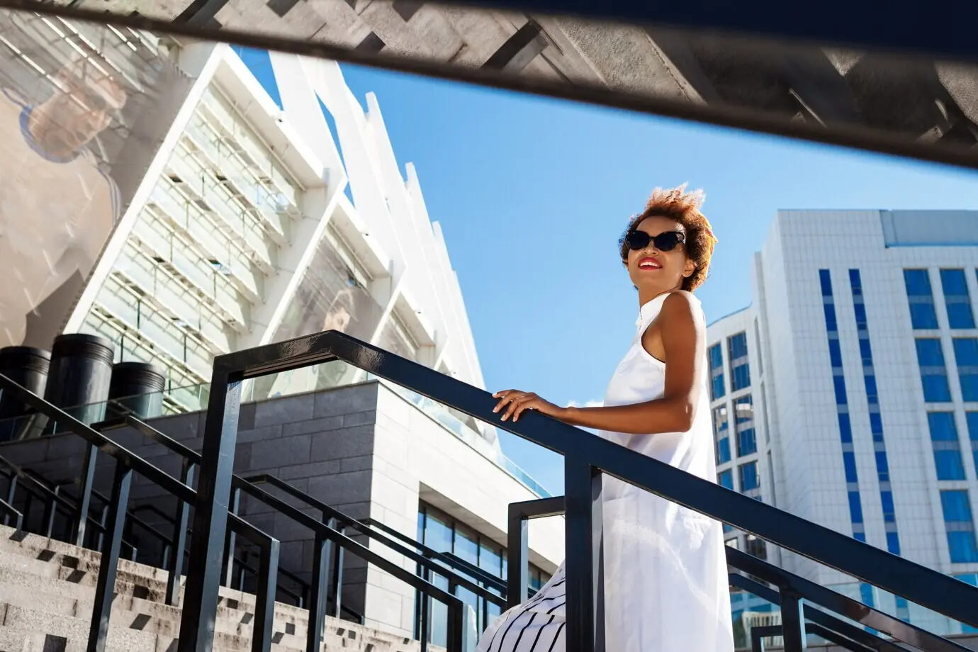 A young, beautiful woman ascends stairs while walking down in the city.